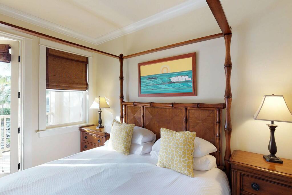 Luxurious bedroom at Kauai Villas featuring a four poster bed and a window with a view.